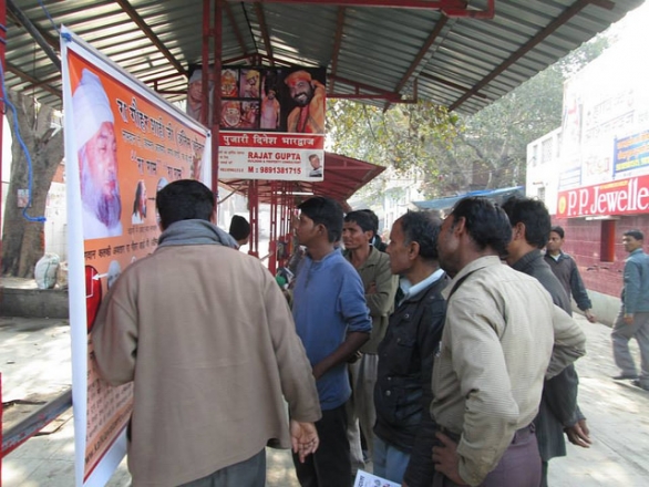 People crowd around a banner depicting the images of Kalki Avatar Ra Gohar Shahi and His divine signs (Kalka Mandir, New Delhi, 