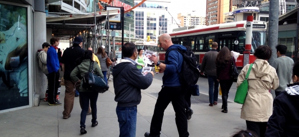 A man takes a leaflet bearing the images of HDE Gohar Shahi in Dundas Square, Toronto.